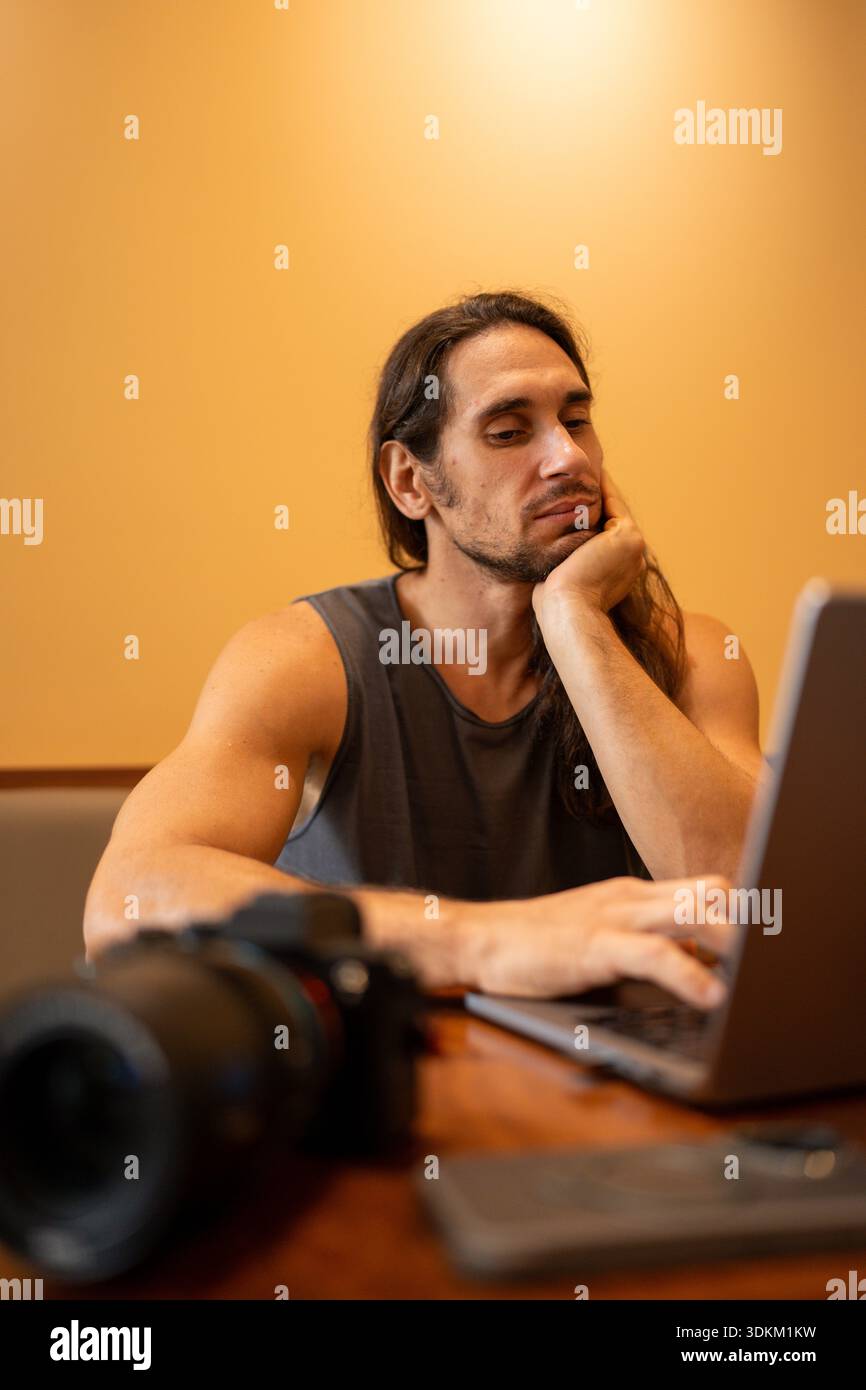 Male content creator working on laptop with camera Stock Photo