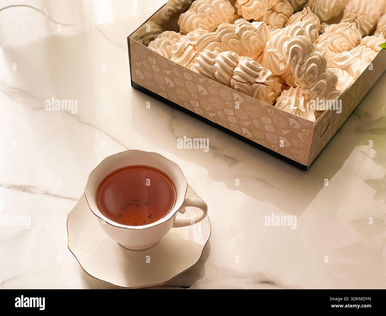 Tea with Zephyr Marshmallows. Cozy tea time with a cup of hot black tea and soft airy Russian zephyr marshmallows on a light table near the window. - Smartphone Captured Stock Image