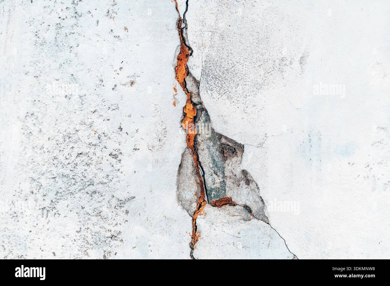 Texture of a weathered gray concrete wall split by a deep jagged crack as background Stock Photo