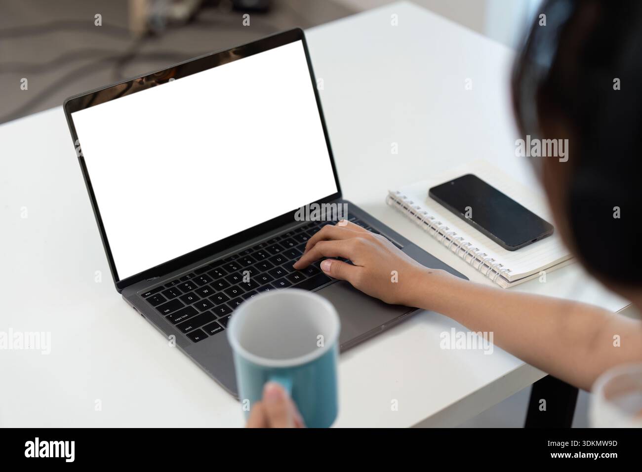 Home Office. Young professional working on laptop with coffee cup in hand. Stock Photo