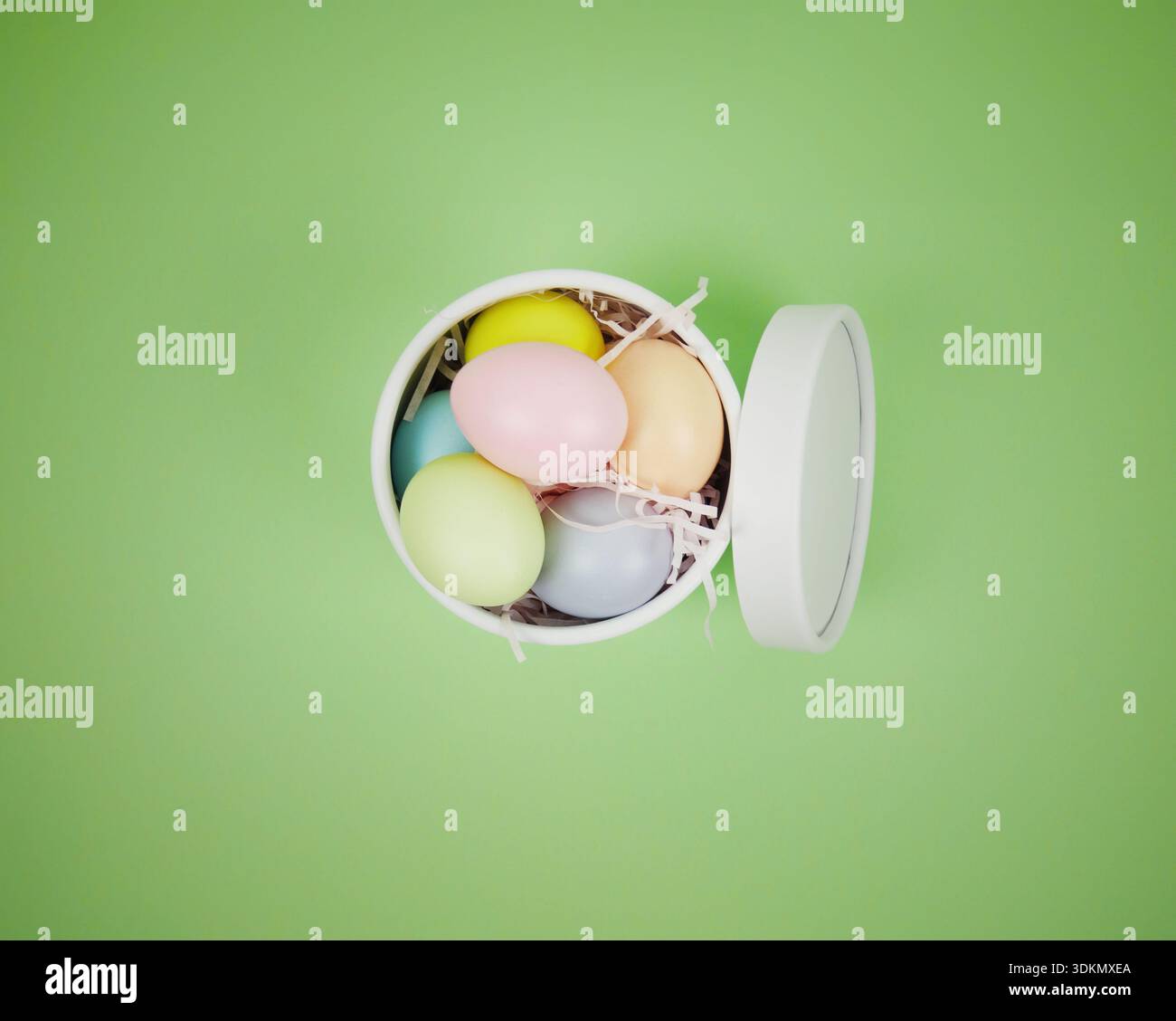 Easter holiday background. Colorful eggs are placed in a white round box on a green surface Stock Photo