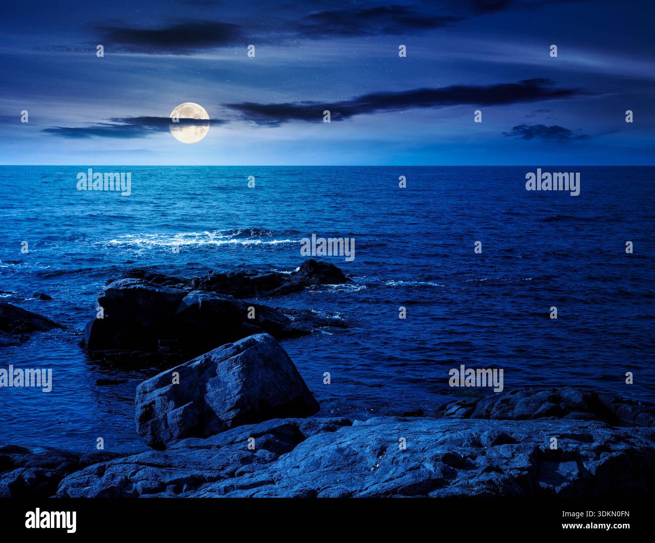 rocky shore of the sea coast under blue sky at night. beautiful view of coastal scene in full moon light. resort scenery during vacation season in sum Stock Photo