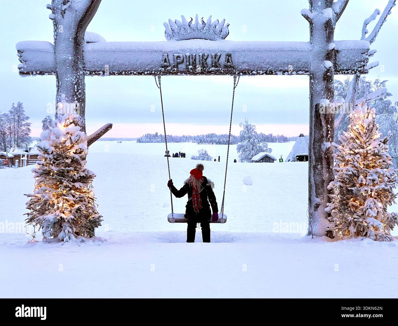 A woman sits on a snowy outdoor swing at the Apukka Resort, Rovaniemi, Finland Stock Photo