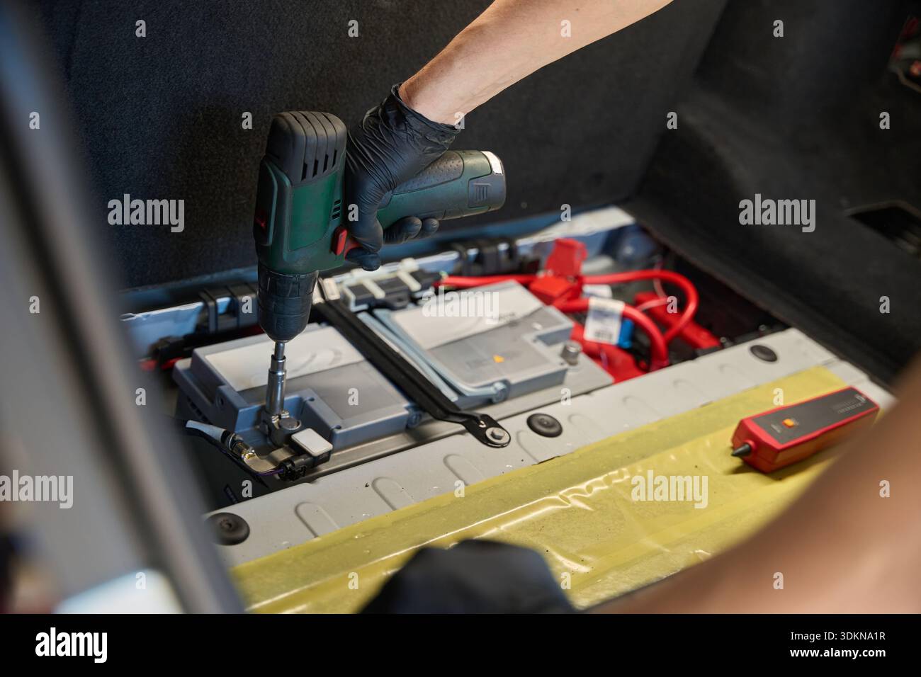 Worker secures a part in the trunk with a tool Stock Photo