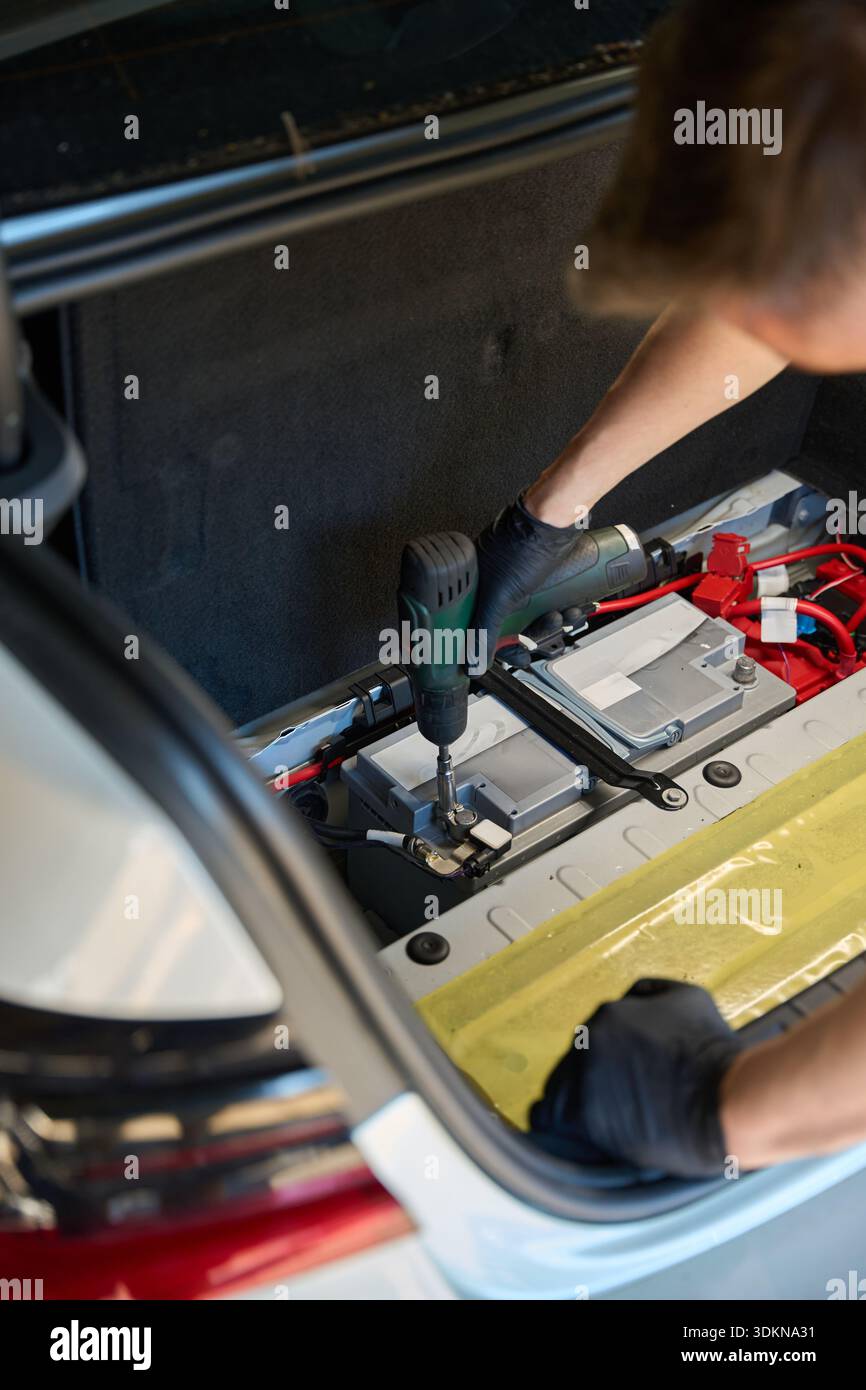 Mechanic uses a drill for work in the trunk Stock Photo