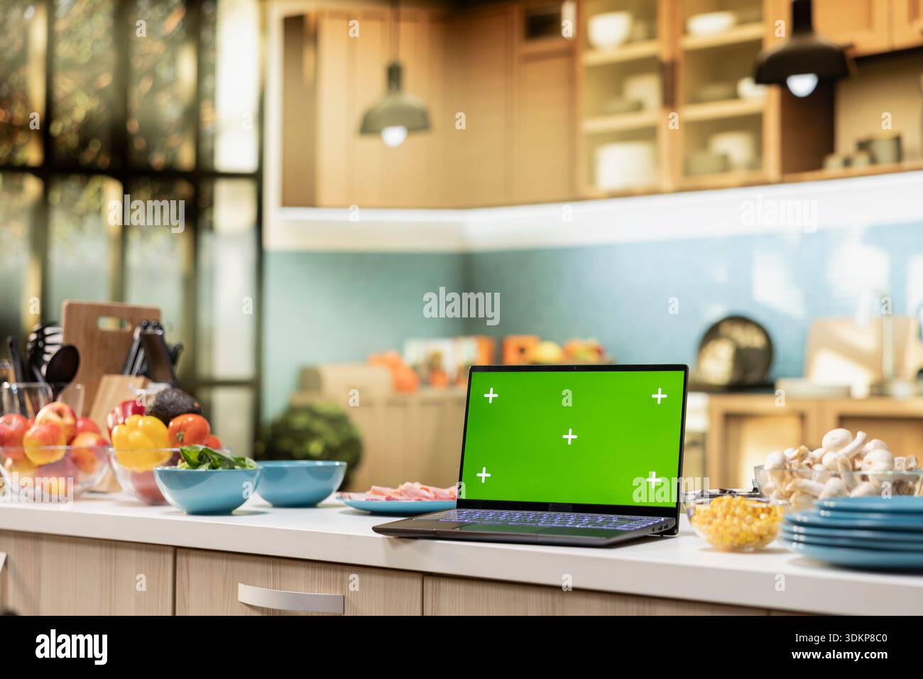 Isolated mockup laptop with modern kitchen interior and countertop. Stylish decorations with kitchenware, fresh produce and spices representing culinary lifestyle and clean household. Stock Photo