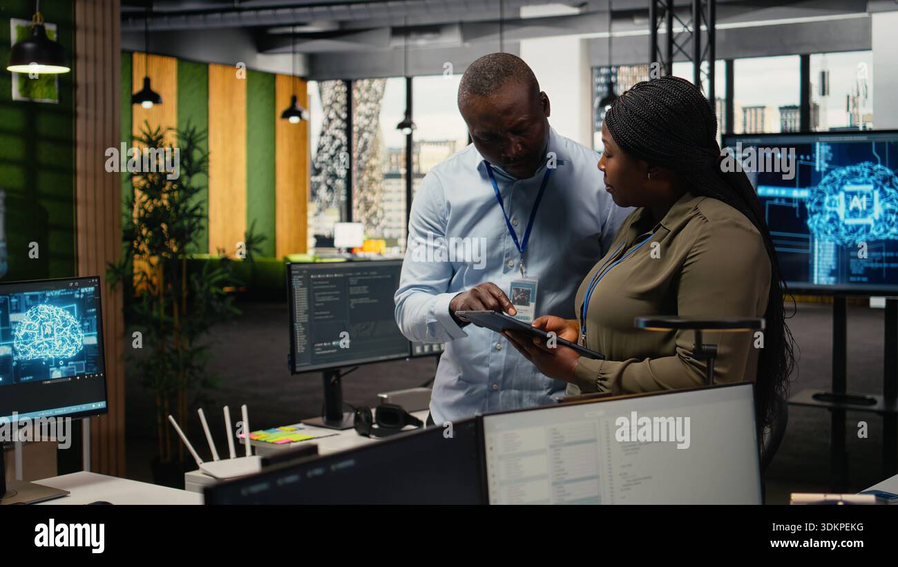 Team of software developers in office automating workflows using artificial intelligence. IT staff members refining deep learning computational models for faster processing, camera A Stock Photo