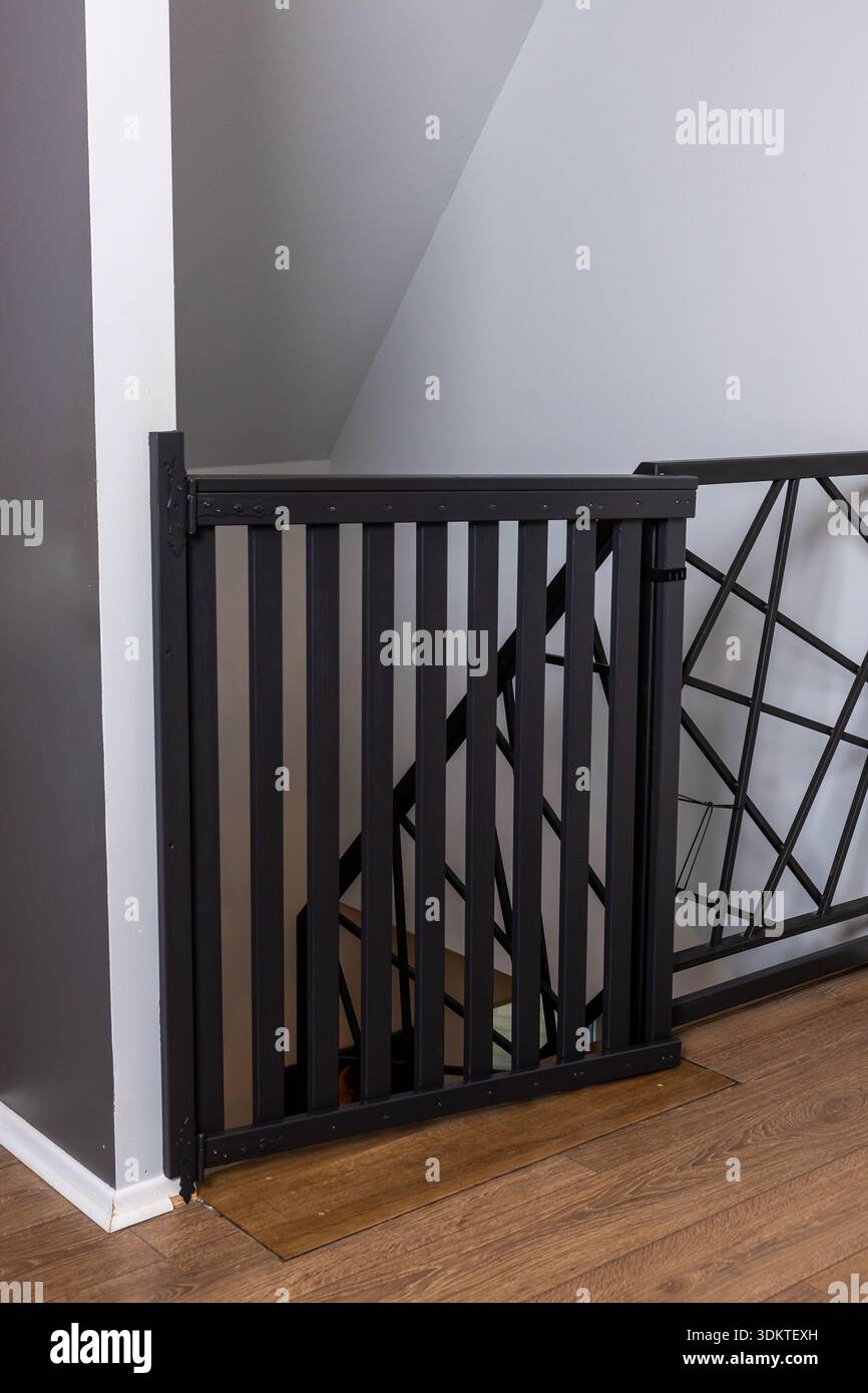 Black safety gate with vertical slats and latch mechanism, adjacent to ...