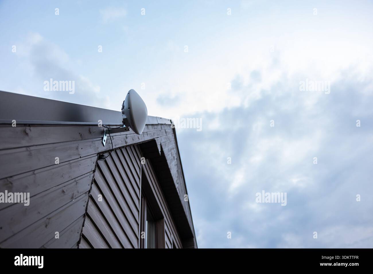 Corner of a wooden house with slanted roof, featuring a white dome ...