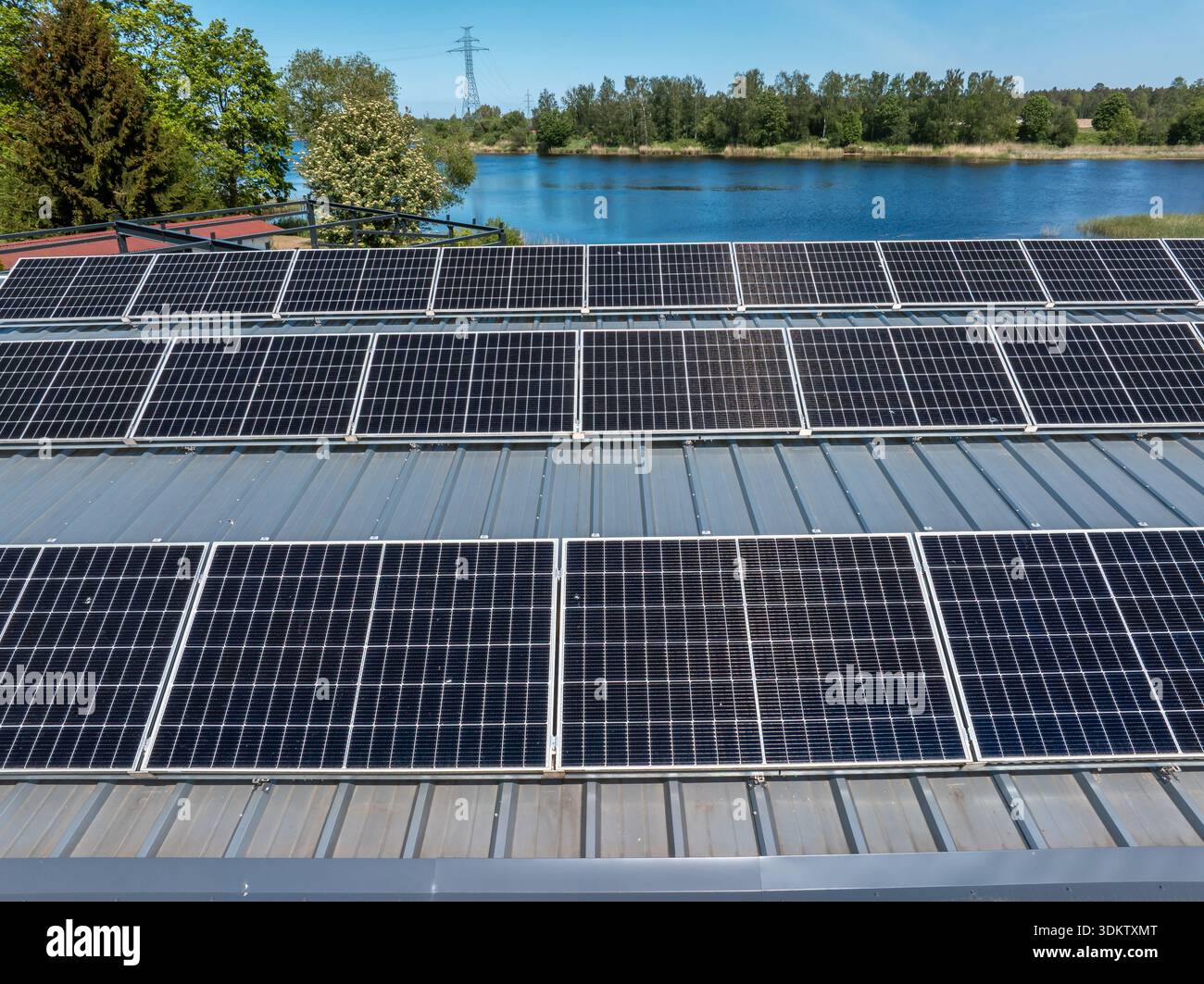 Metaaidc Solar Power Metallic rooftop with solar panels, a body of water, and a line of ...