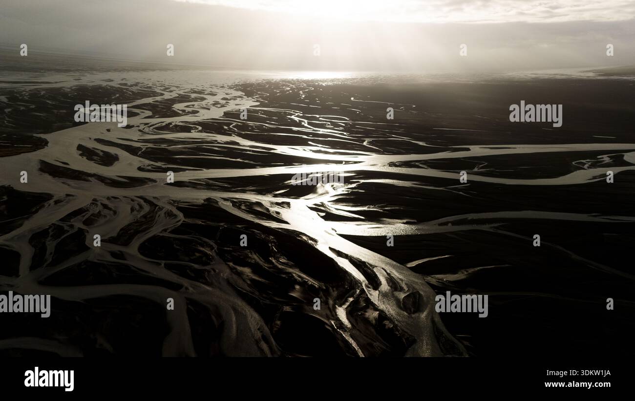 With Rivers Raring Below Aerial view of glacial rivers carve through the dark earth under a ...