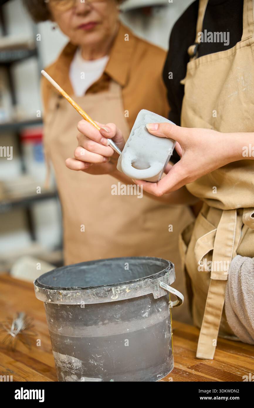 Craftswoman covers a clay sample with a special solution Stock Photo ...