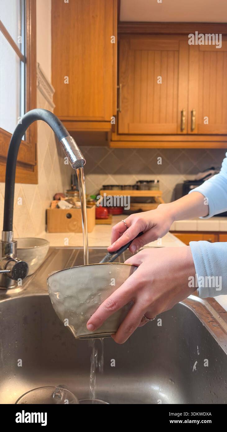 Washing dishes by hand in home kitchen under running water - Smartphone Captured Stock Image