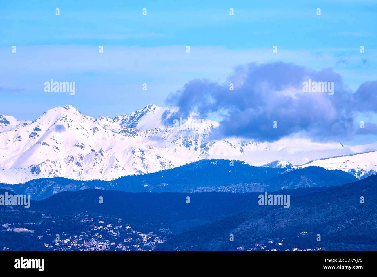 Snow-Capped Mountain Range Under Clear Blue Sky With Clouds and Rolling Foregrounds Stock Photo