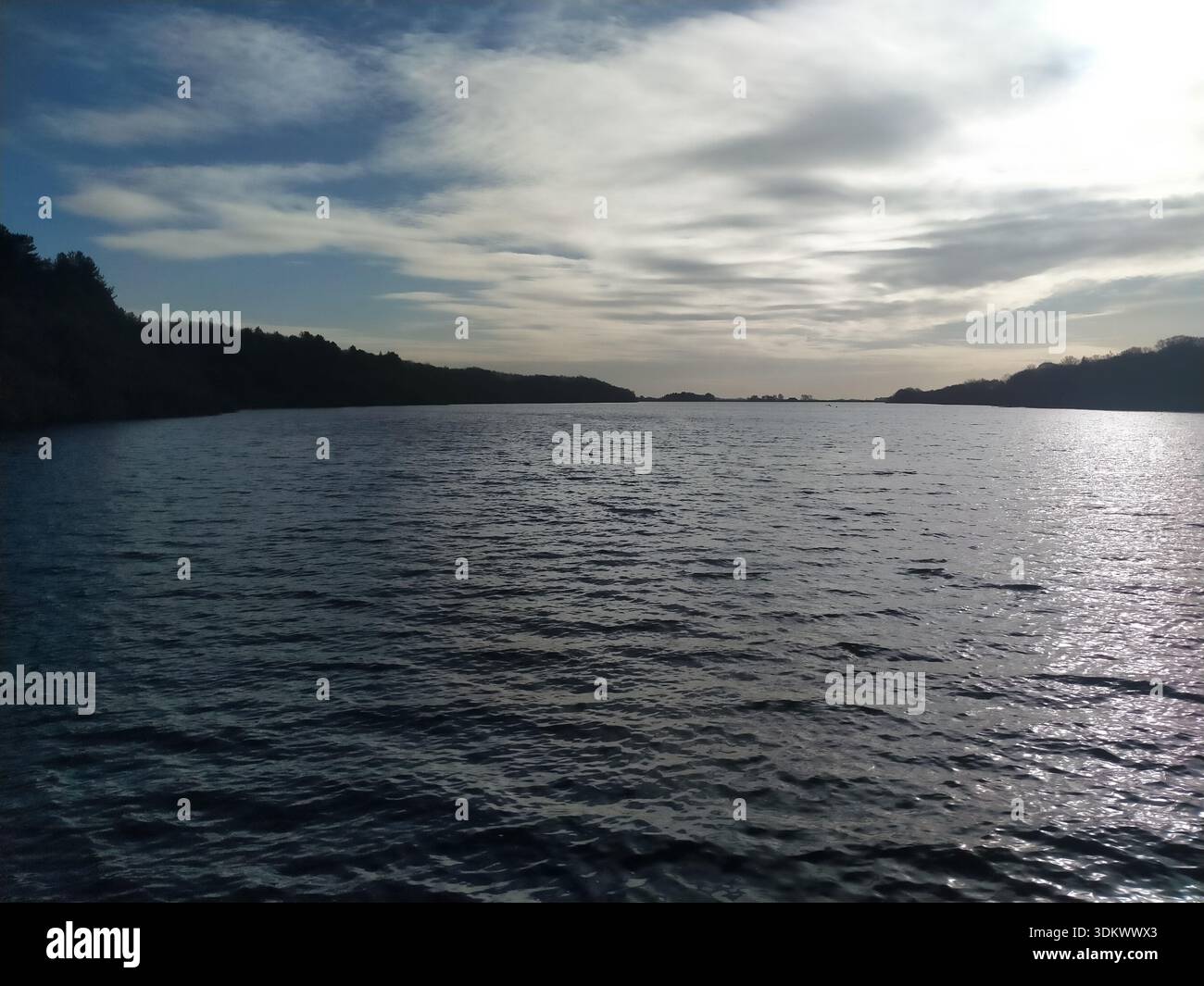 Wide reservoir view with gentle ripples on the water, distant hills and soft evening light under layered clouds. - Smartphone Captured Stock Image