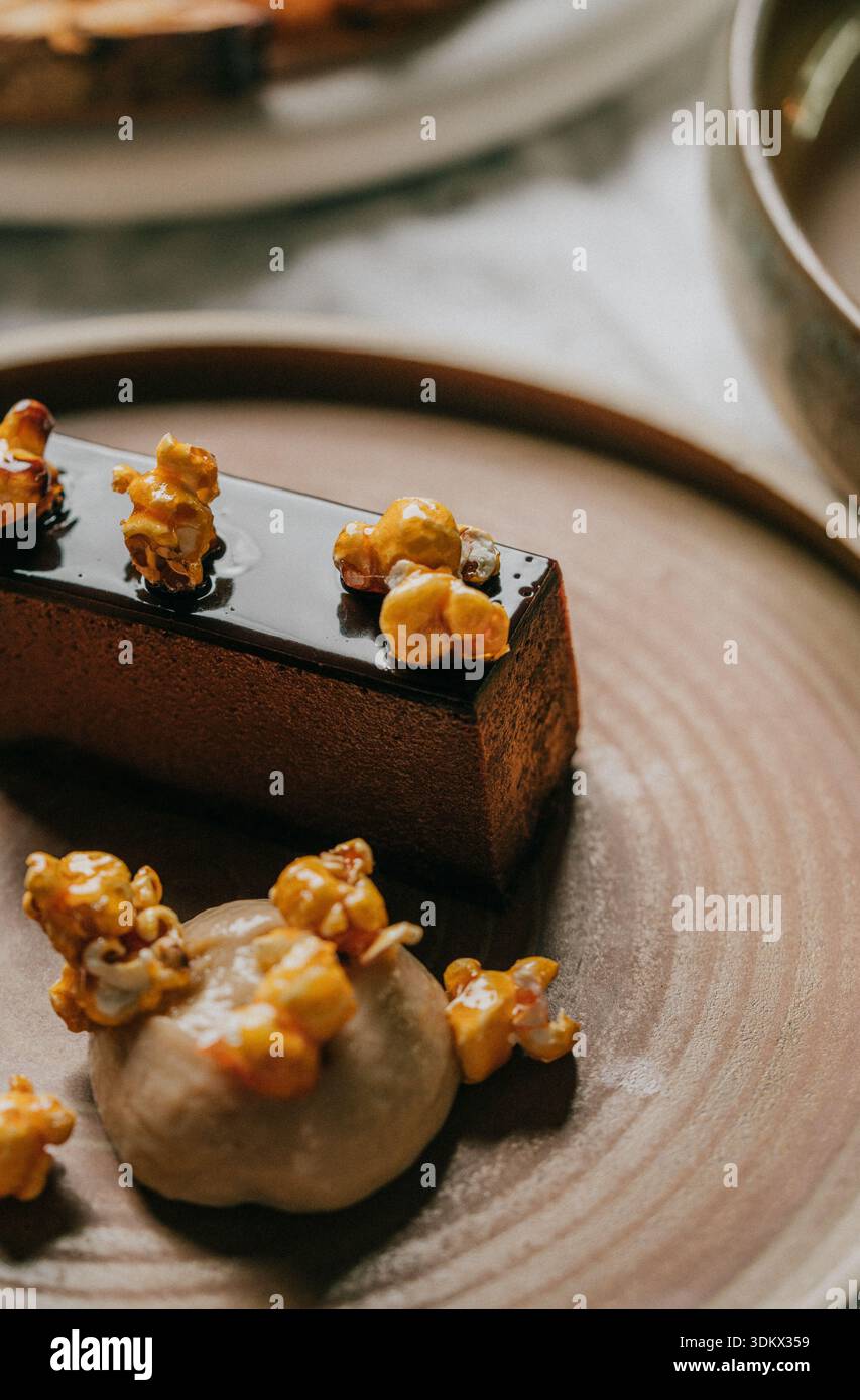 A dessert with a brown crust and a layer of caramel on top. The dessert is topped with popcorn and is served on a brown plate Stock Photo