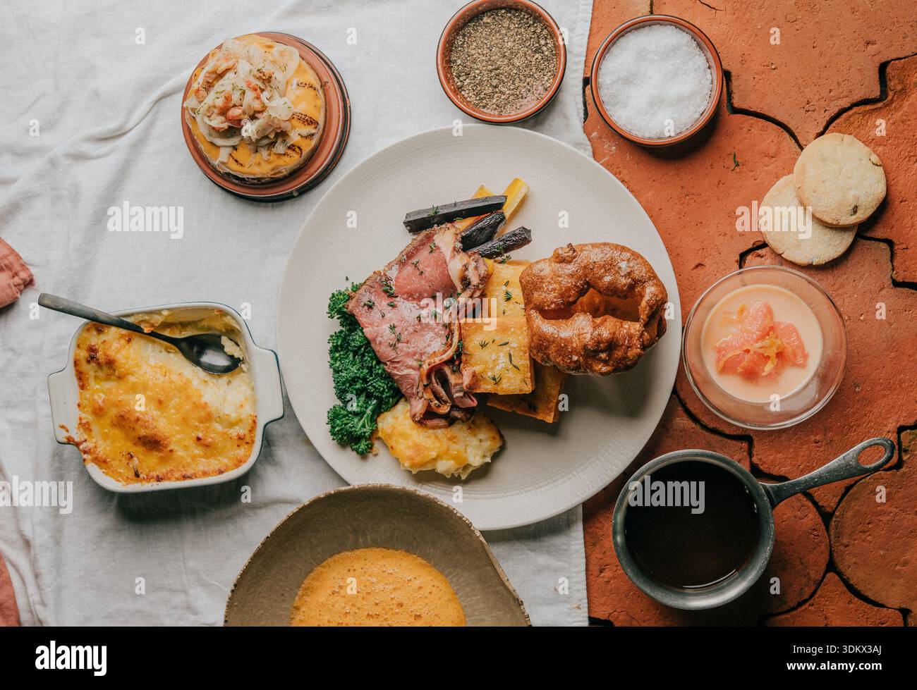 A plate of food with a variety of dishes including a pie, a cake, and a bowl of soup Stock Photo