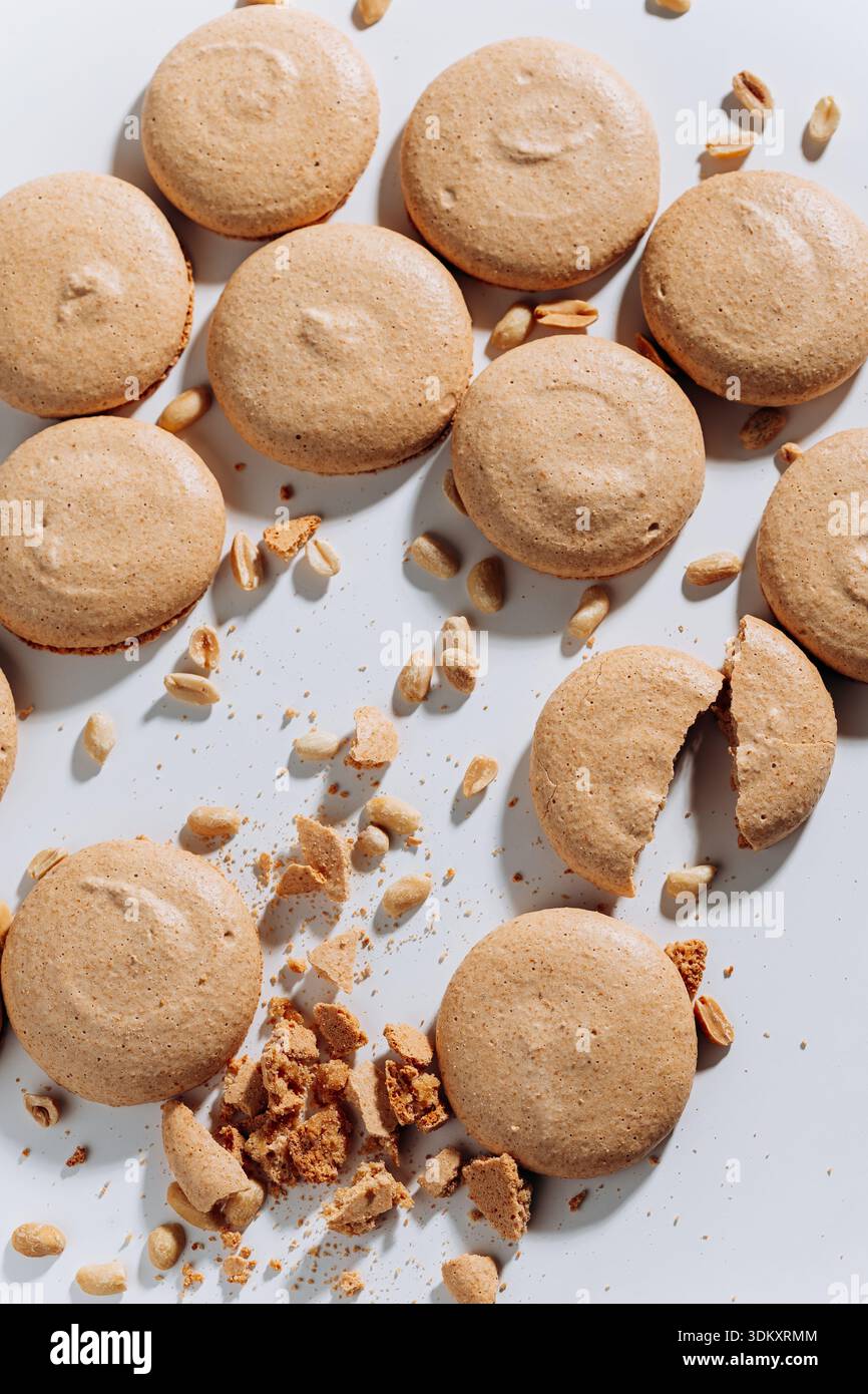 Peanut macaron cookies with crumbs and nuts on white, top view, hard light Stock Photo