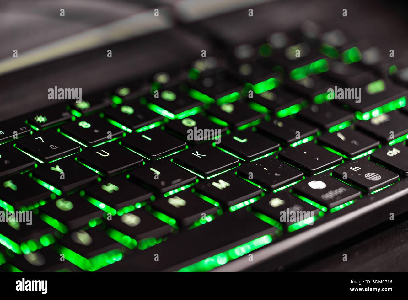 Close up of a laptop keyboard with green backlit keys, technology concept, programming, cybersecurity, gaming Stock Photo