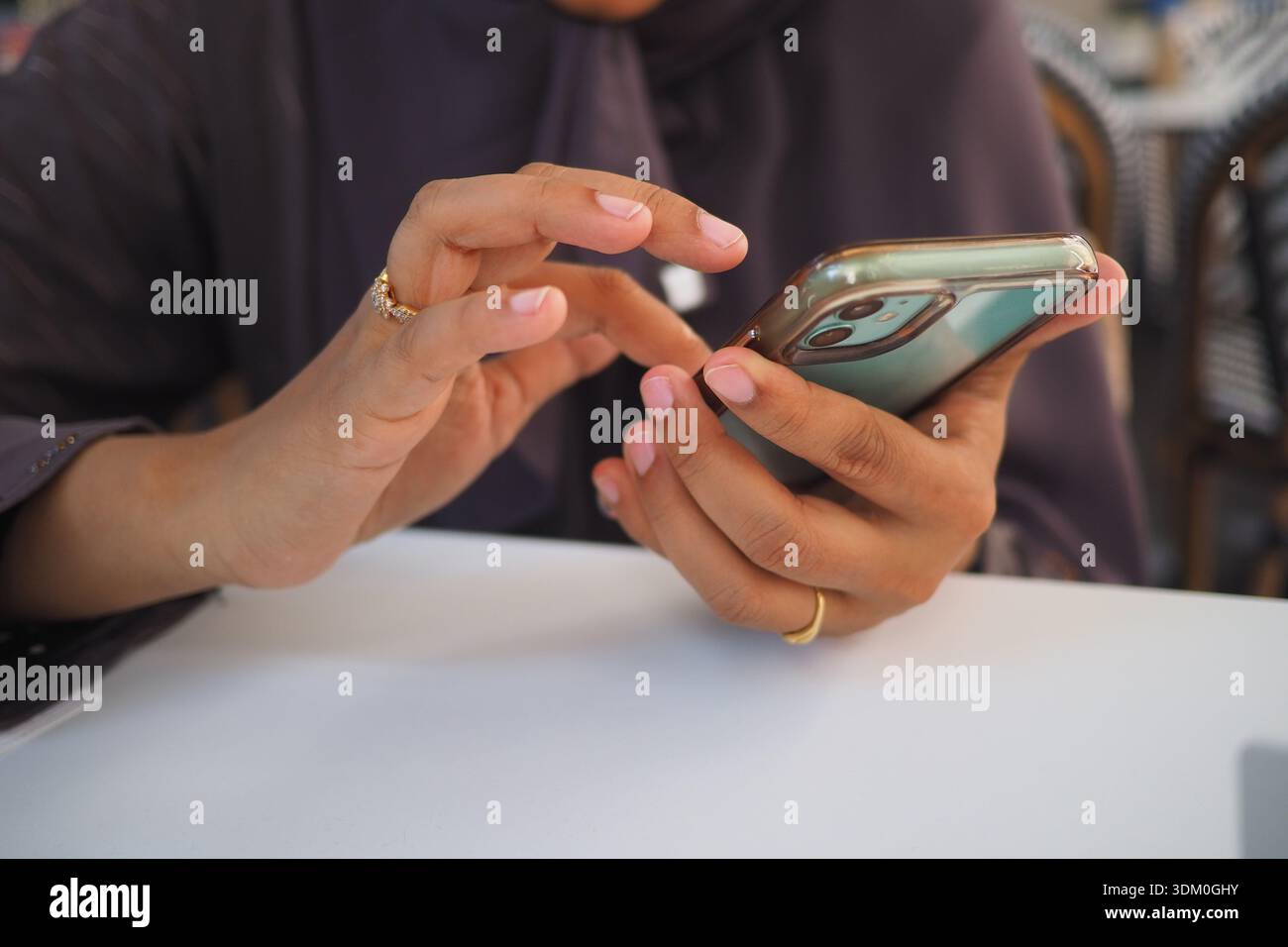 Person uses a smartphone while sitting at a table Stock Photo