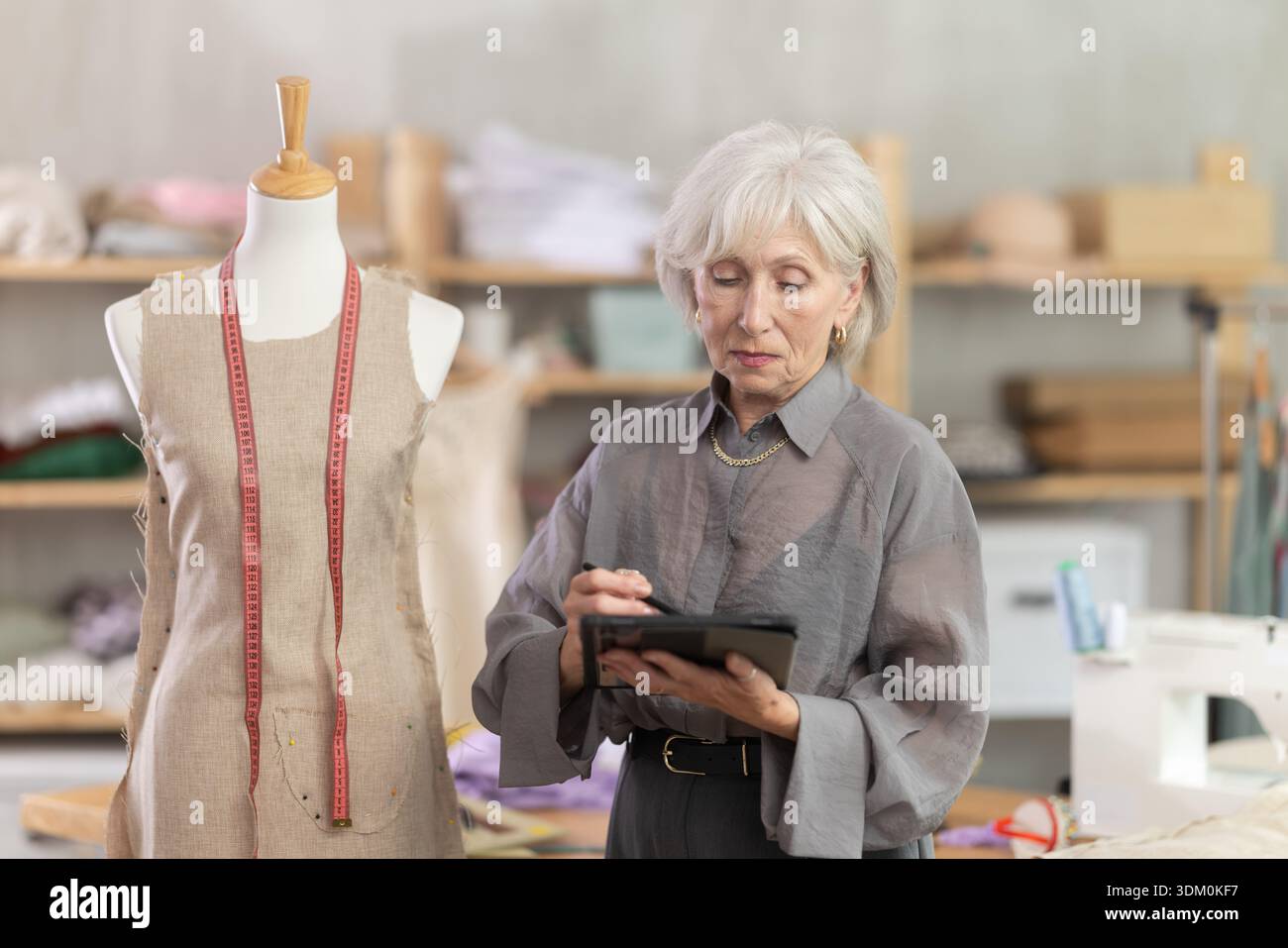 Woman dressmaker makes pattern using tablet Stock Photo