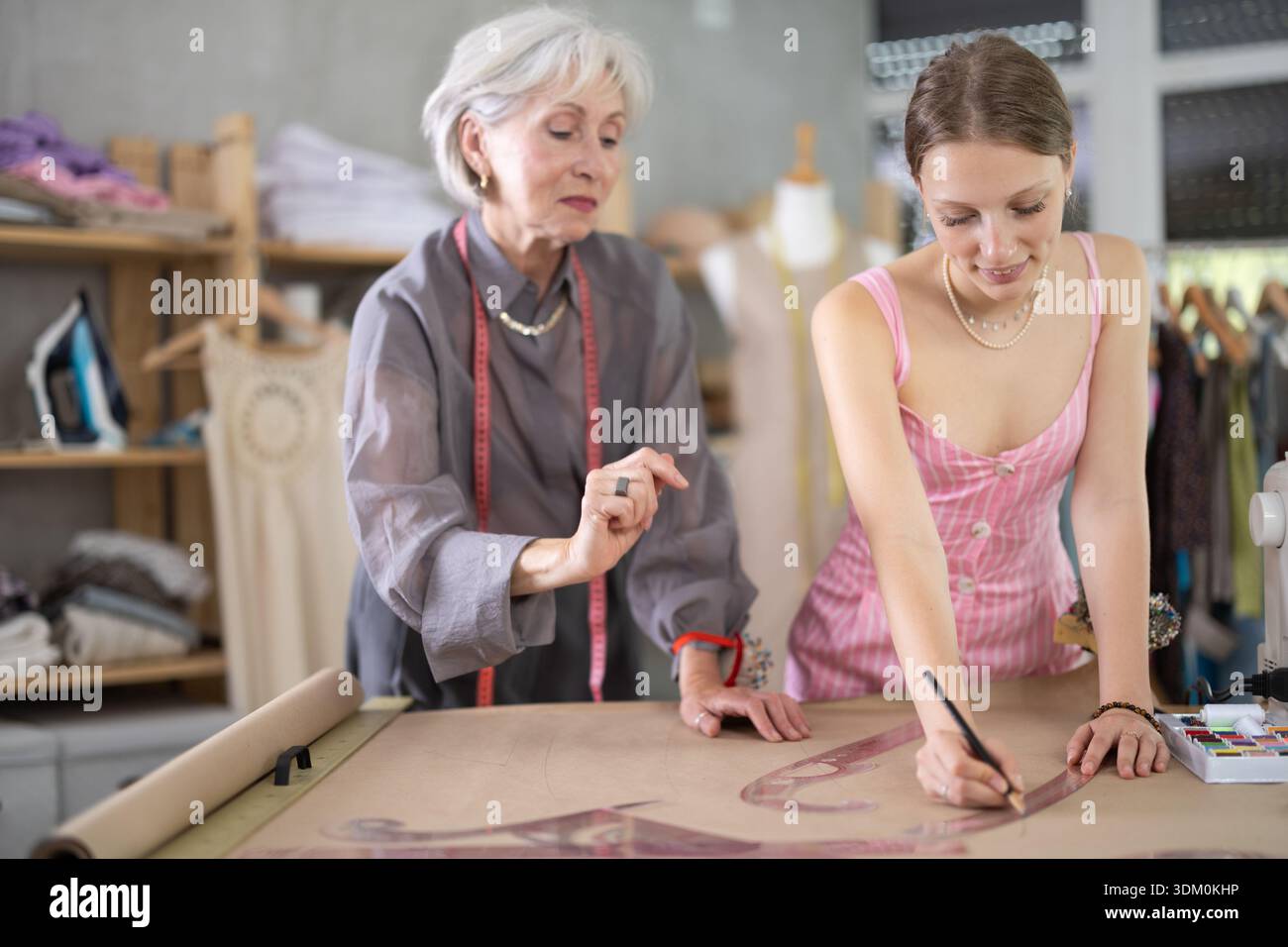 Elderly woman teaches young woman how to draw pattern on paper in ...