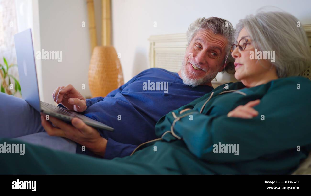 Senior couple relaxing in bed using a laptop Stock Photo