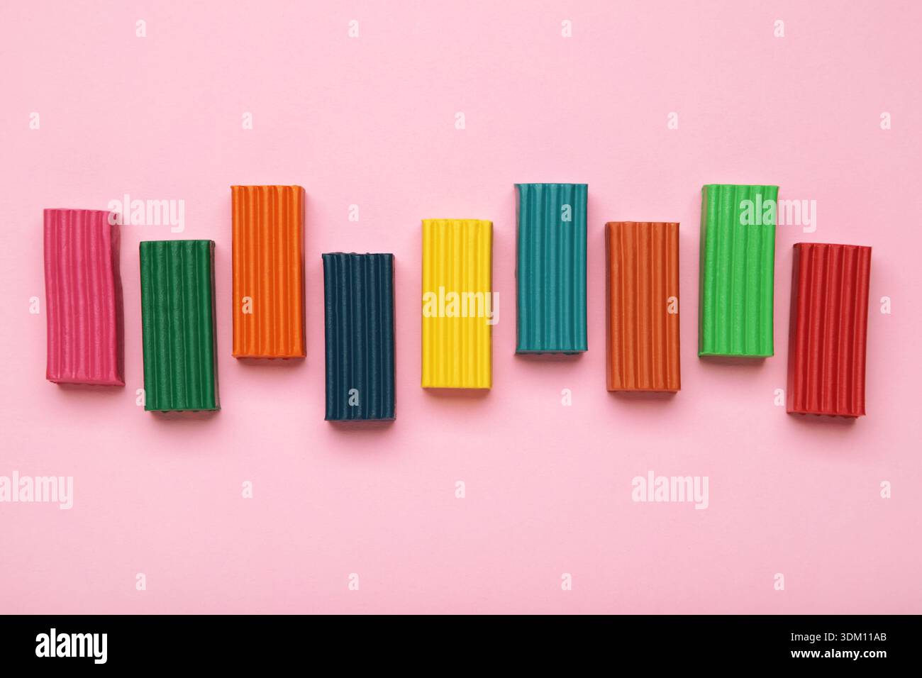 Multi-colored plasticine bricks on pink background. Children's plasticine close-up. Stock Photo