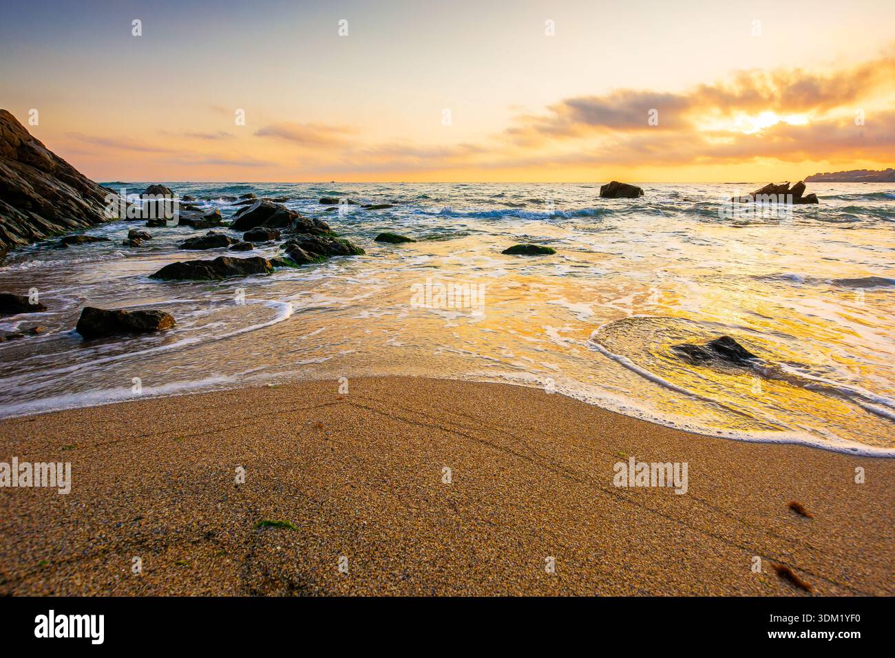 beautiful sunrise over empty sandy beach at the black sea. white foam rolling on to the shore near boulder. perfect summer vacation concept. awesome w Stock Photo