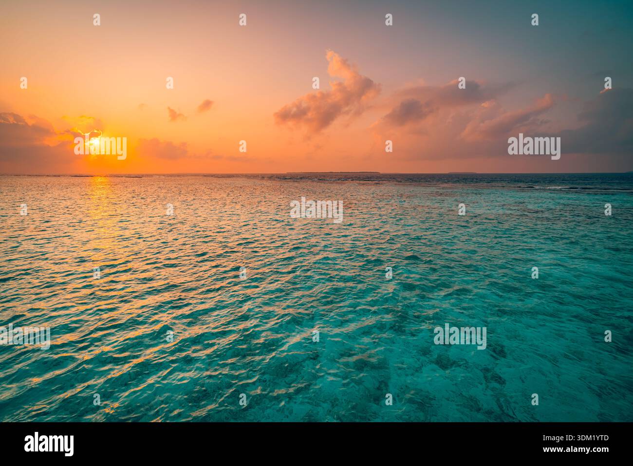 Vivid sunset sun setting over calm tropical sea and coral reef horizon. Warm glowing ocean. Summer vacation travel holiday paradise scenic honeymoon Stock Photo