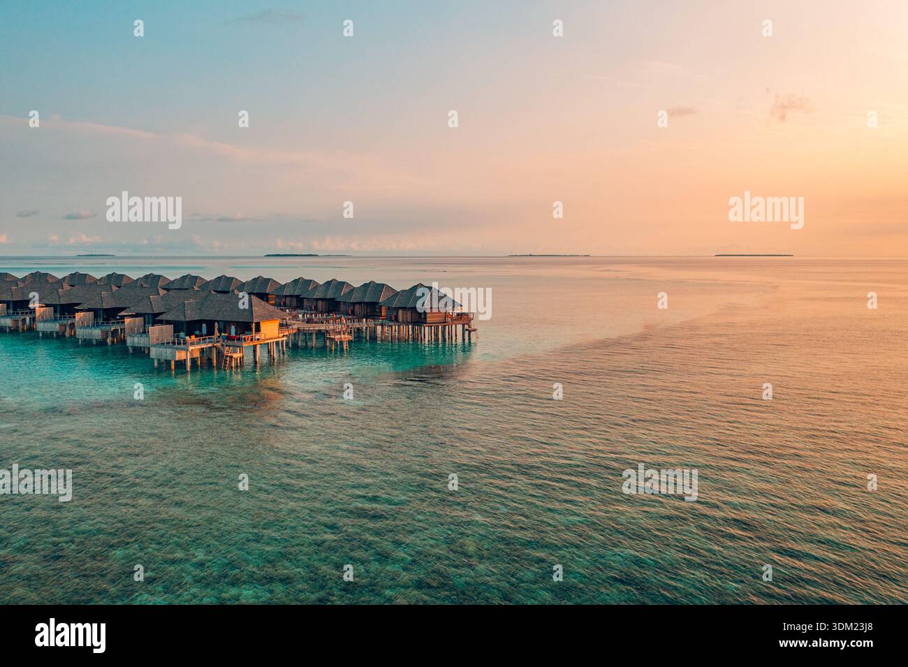 Radiant Maldives aerial overwater villas sunset warm golden sky stunning paradise coastal luxury resort travel destination romantic. Calm vacation art Stock Photo