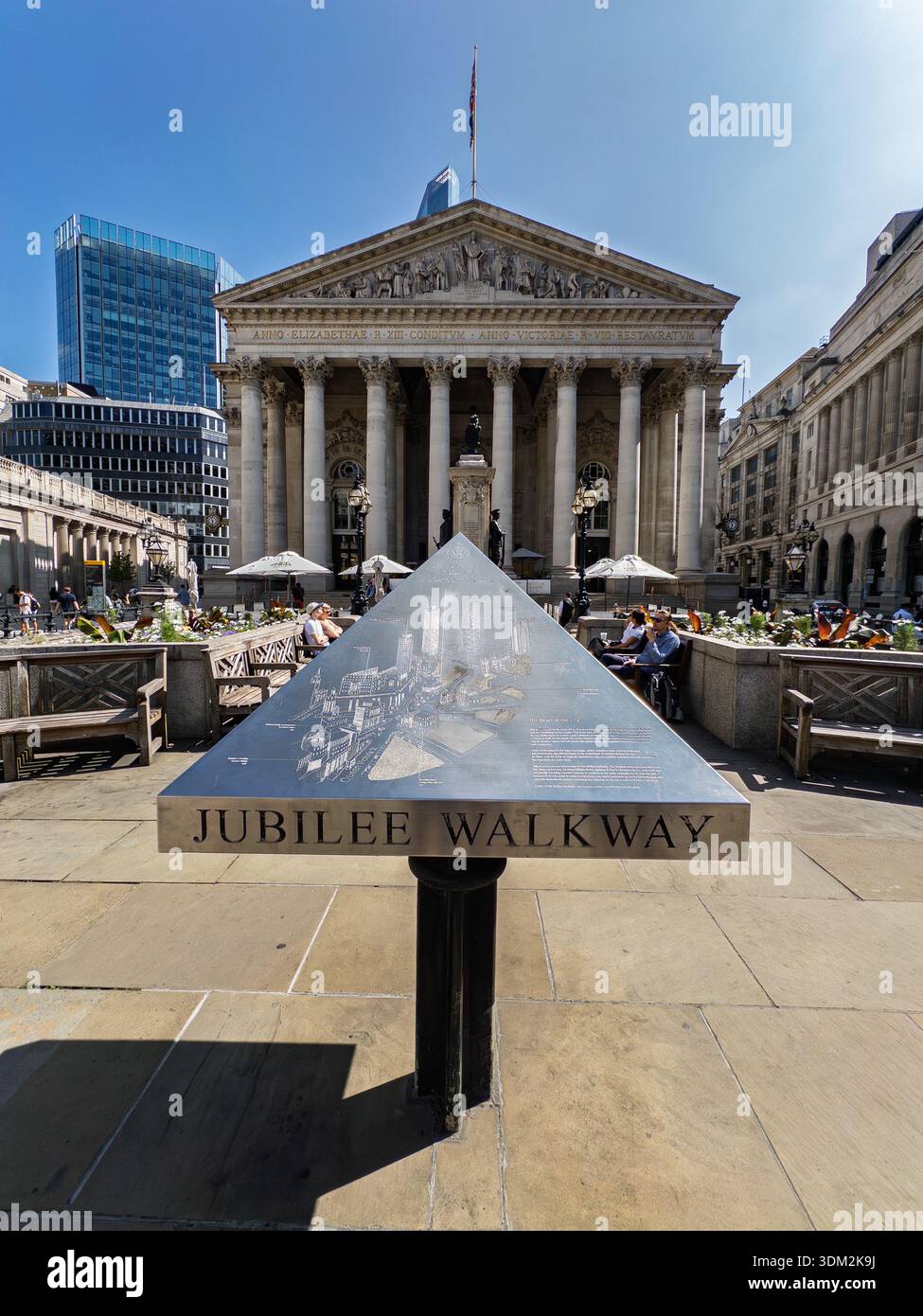 Jubilee Walkway triangular signpost in Bank of England forecourt with grand columns, statues, diners and Union Jack flag under sunny skies - Smartphone Captured Stock Image