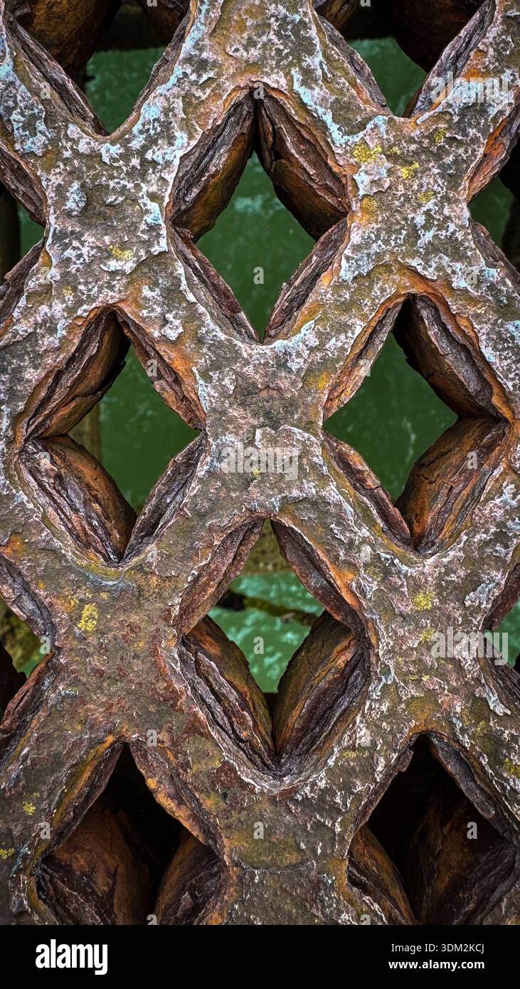 Close-up of rusted iron lattice walkway on Worthing Pier framing turquoise sea water through diamond apertures - Smartphone Captured Stock Image