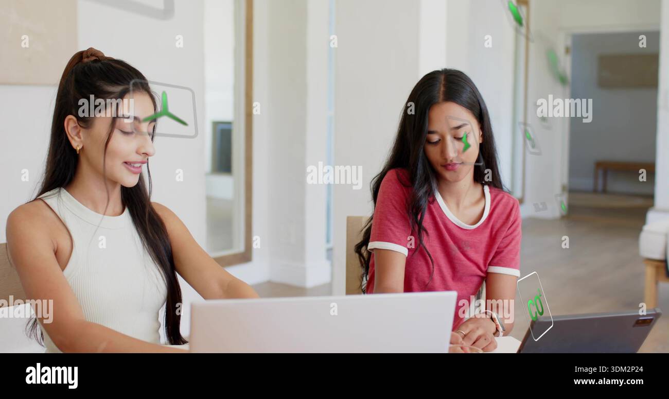 Working two women using laptops in office, wearing sleeveless top and ringer tee, with AR overlays Stock Photo