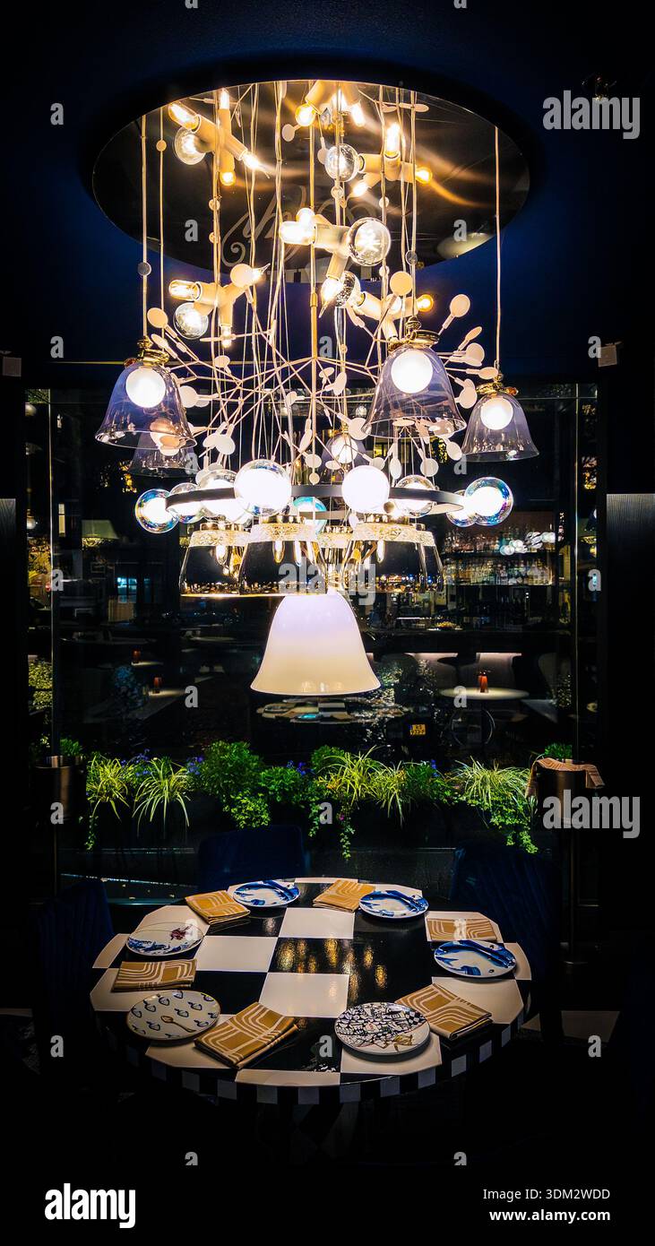 Dining area in Andaz Amsterdam Prinsengracht hotel’s glass-enclosed restaurant, featuring a dramatic gold chandelier with glass shades over a checkere - Smartphone Captured Stock Image