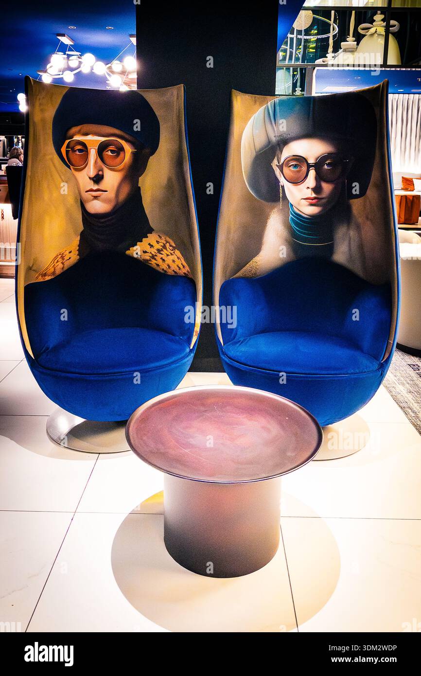 Pair of whimsical blue velvet swivel pod chairs featuring oversized painted portraits of beret-wearing figures in sunglasses at Andaz Amsterdam Prinse - Smartphone Captured Stock Image