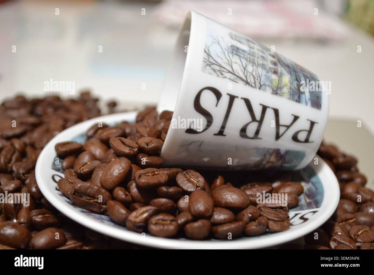 Coffee beans spilling from Paris souvenir cup Stock Photo