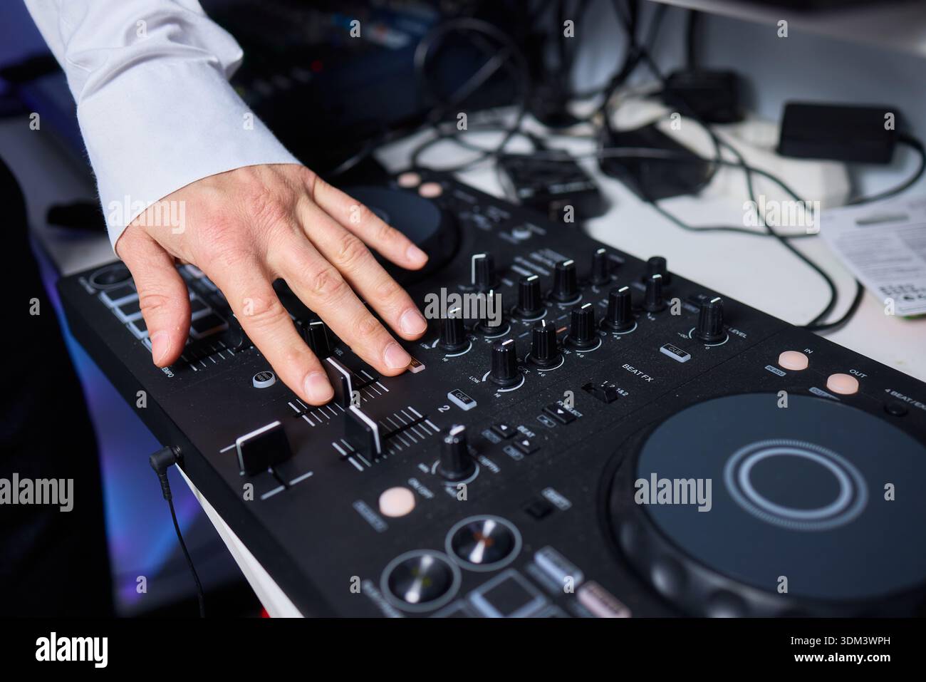 Electronic DJ controller in action. Hands adjusting colorful DJ ...