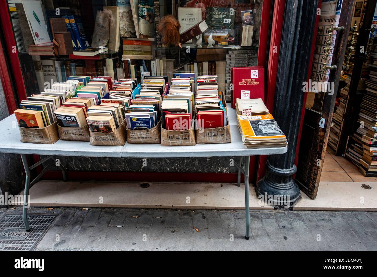Secondhand books for sale on a sidewalk table outside El Asilo del Libro, a historic bookstore in Valencia, Spain, featuring vintage charm and art. Stock Photo