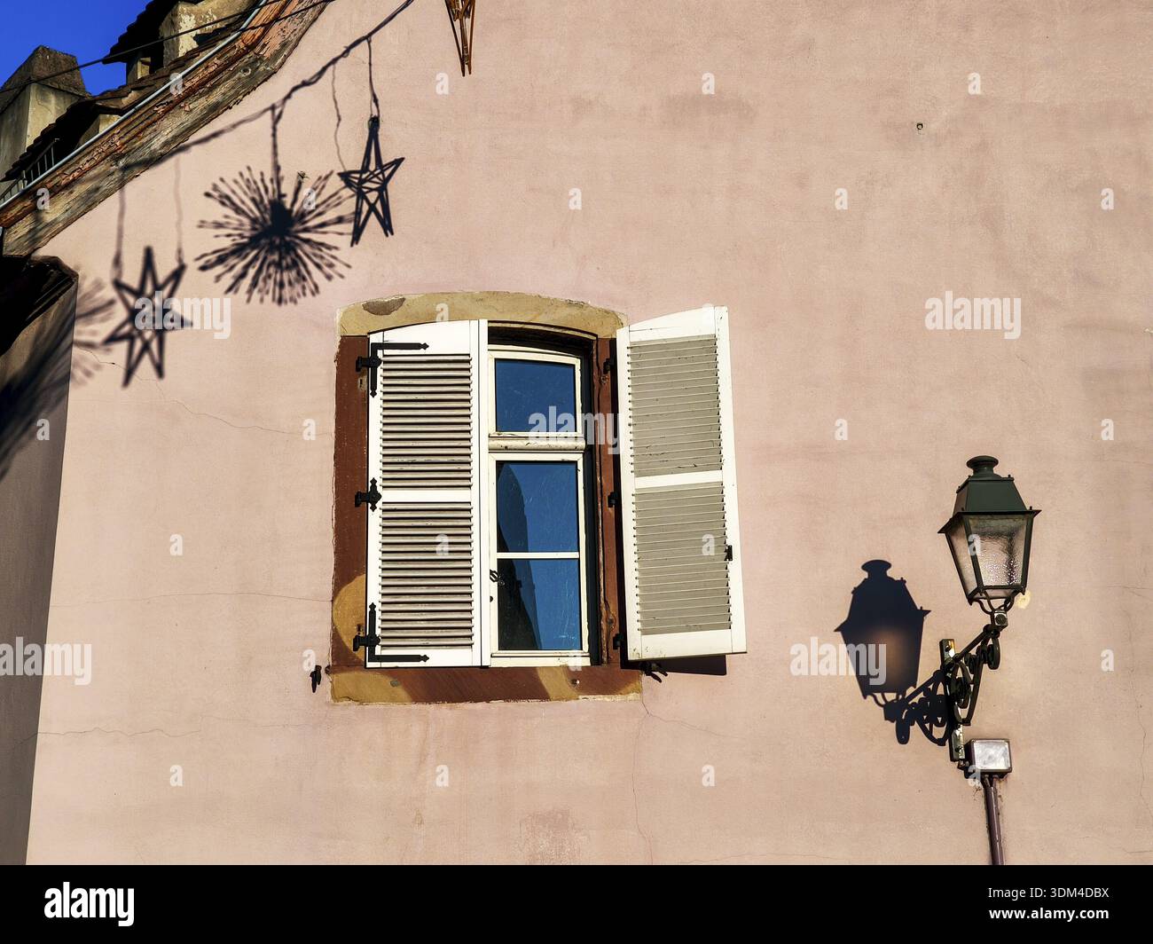 Pink facade with white window and antique street lamp whose shadow falls on the wall, Old Town, Strasbourg, Bas-Rhin, Alsace, France Stock Photo