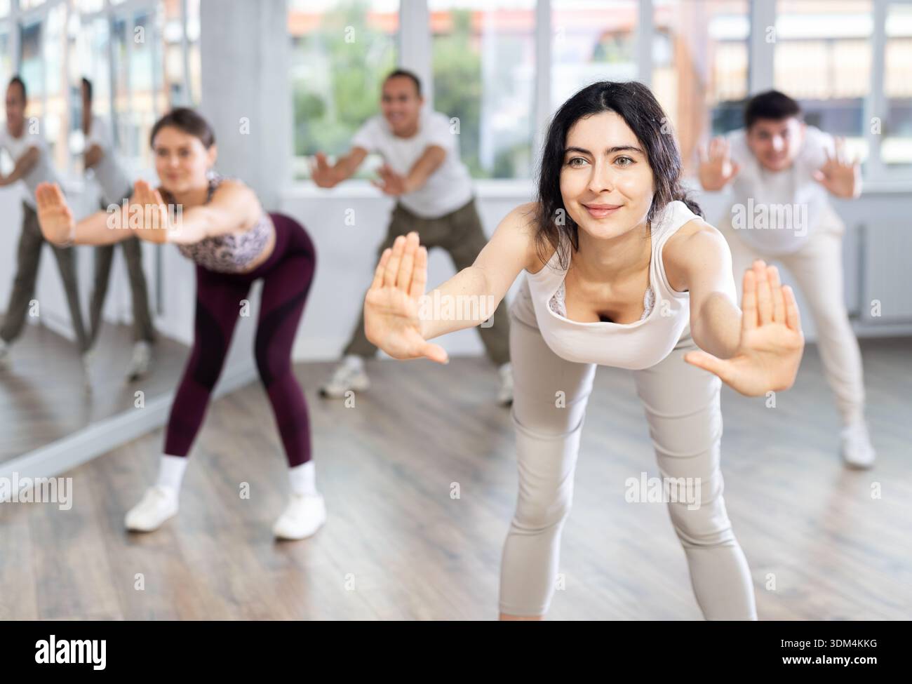 Young brunette warming up with group in dance class Stock Photo