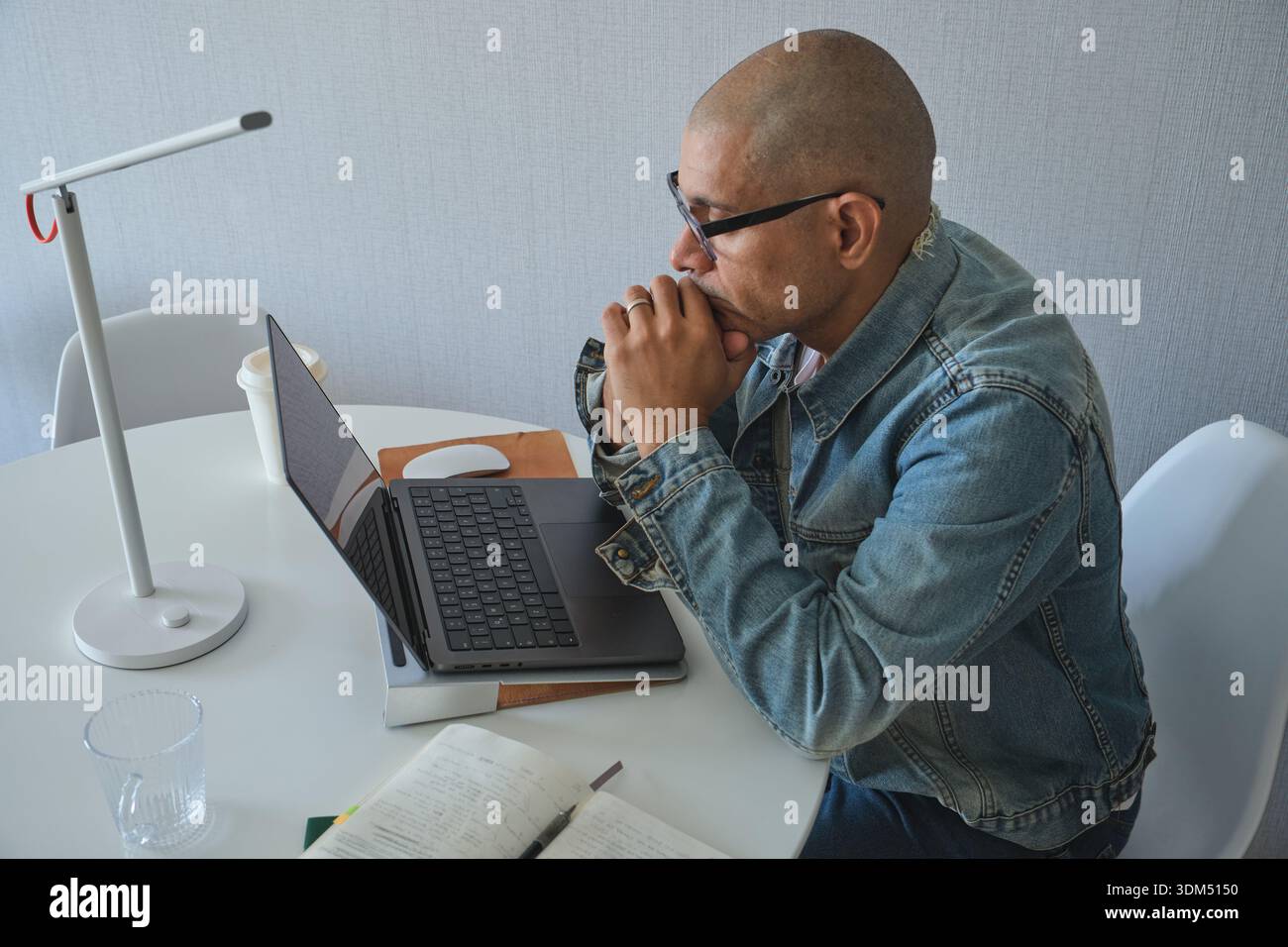Bald man working remotely, concentrating on laptop research and problem-solving Stock Photo