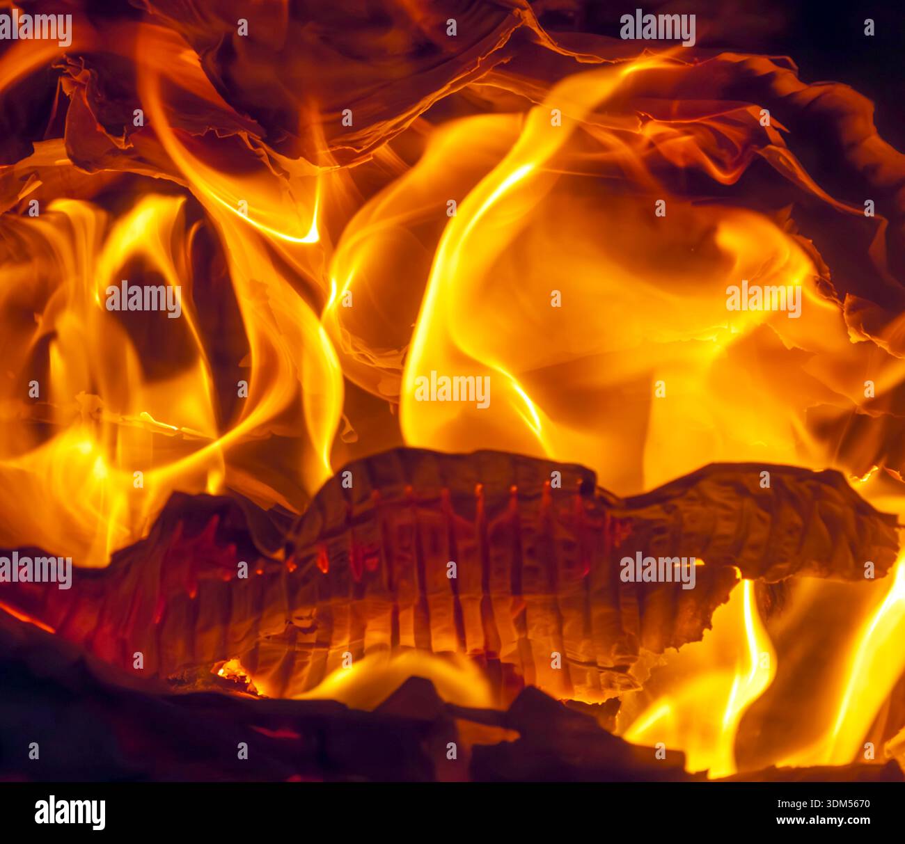 Ribbed cardboard packaging burning on a wood burner. Stock Photo