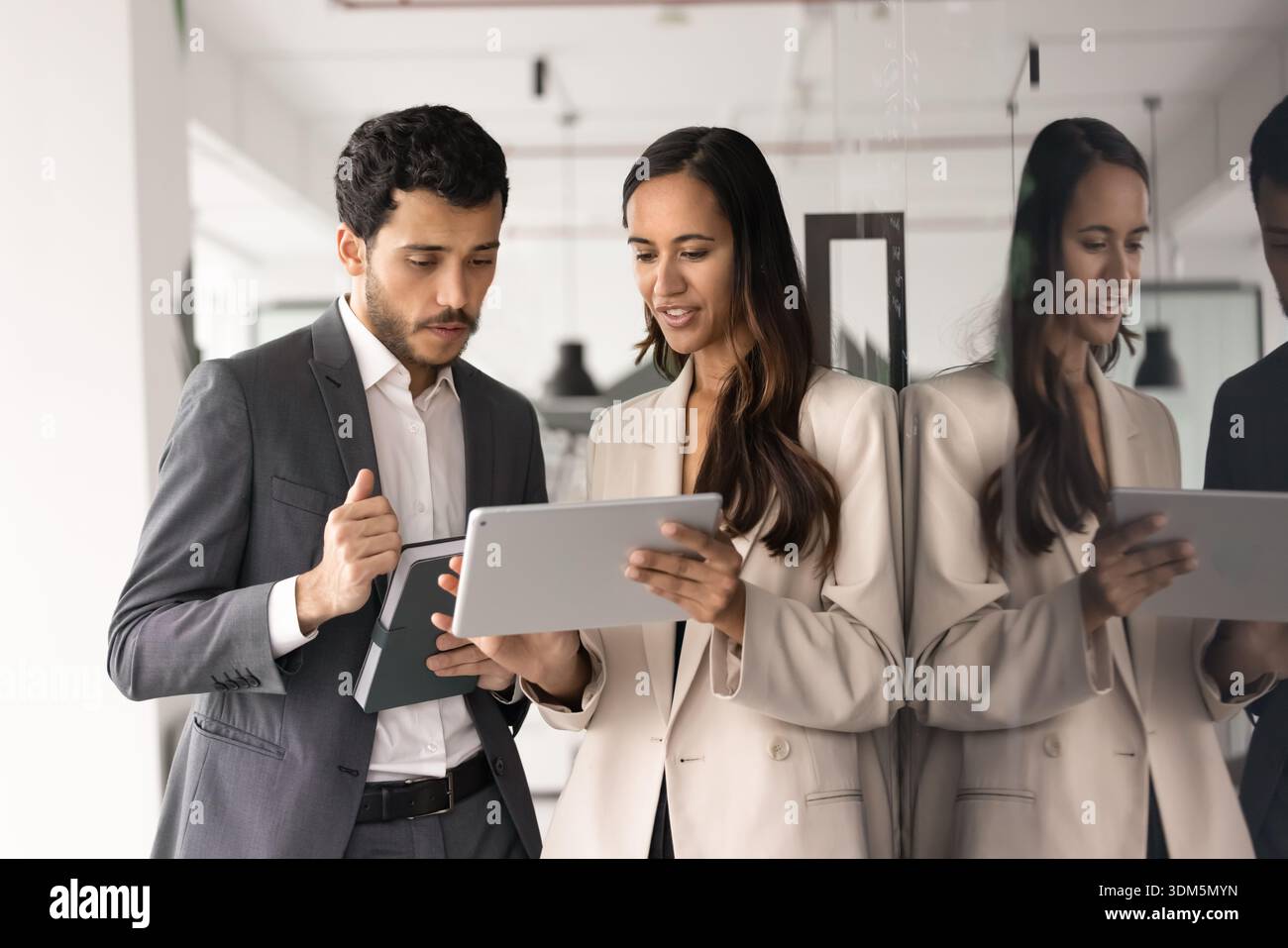Two focused employees using tablet, working on joint task Stock Photo