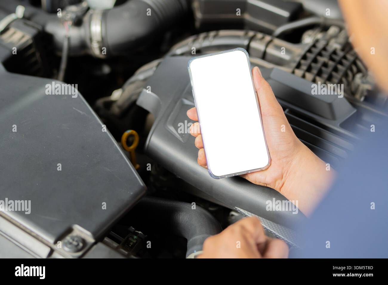 Close up hand using mobile phone with blank screen with broken car. Phone on mechanic hand holding in car repair shop. Copy space. Stock Photo