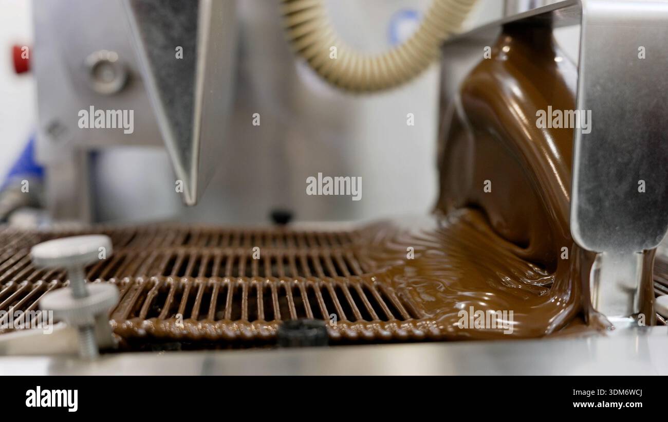 Liquid chocolate pouring on conveyor belt in factory Stock Photo