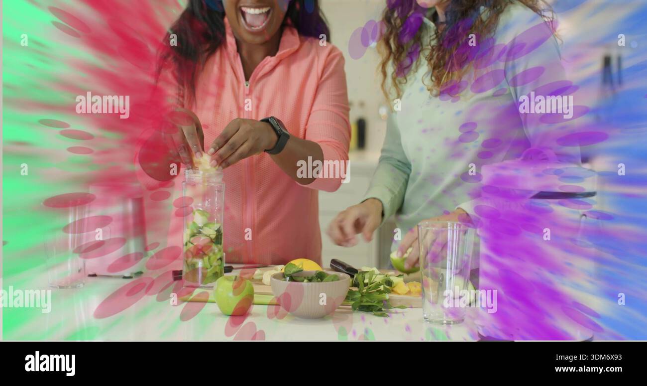 Smiling two women filling infuser container on kitchen counter wearing ...