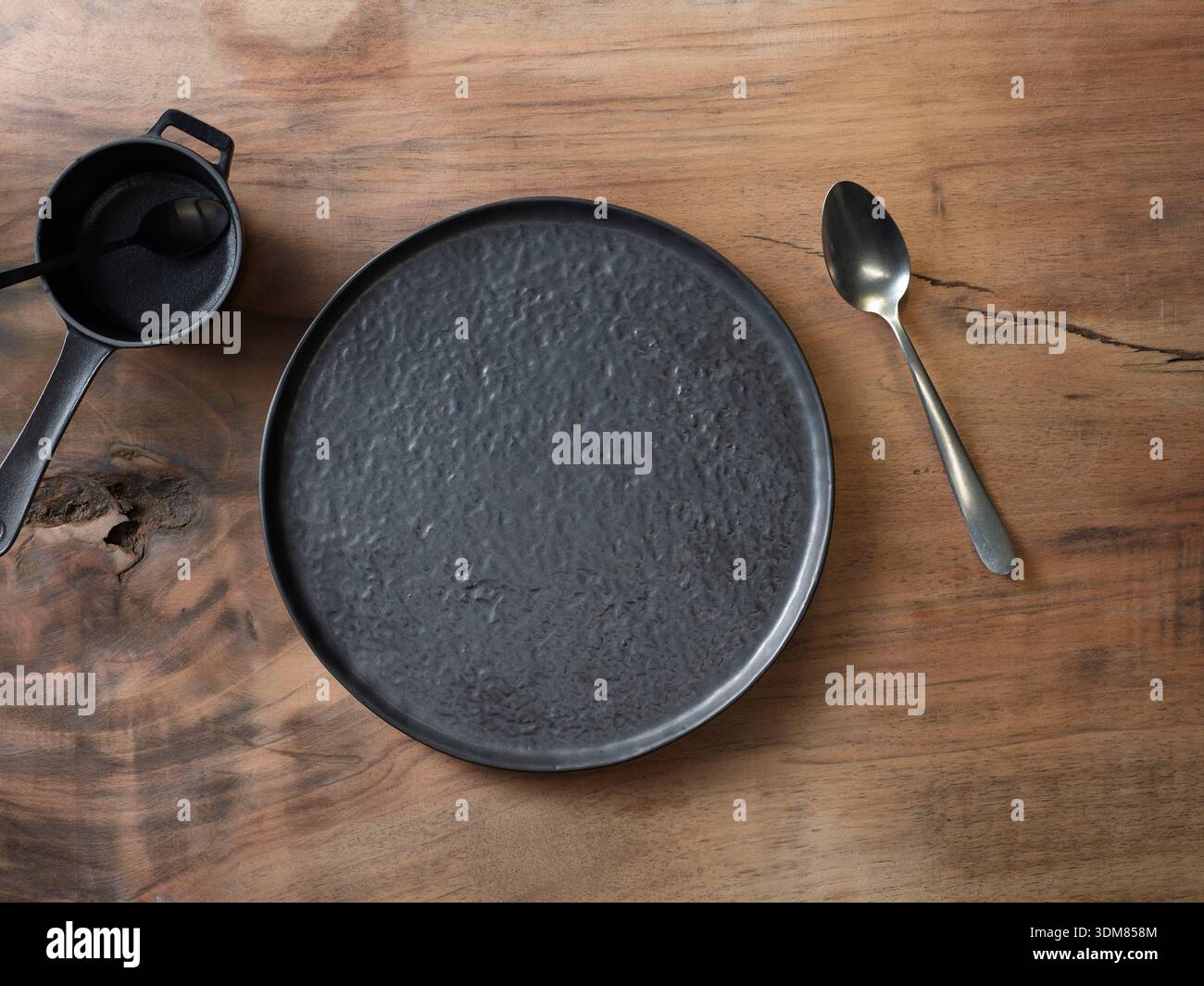 Dark textured ceramic plate on rustic wooden table, top view flat lay Stock Photo