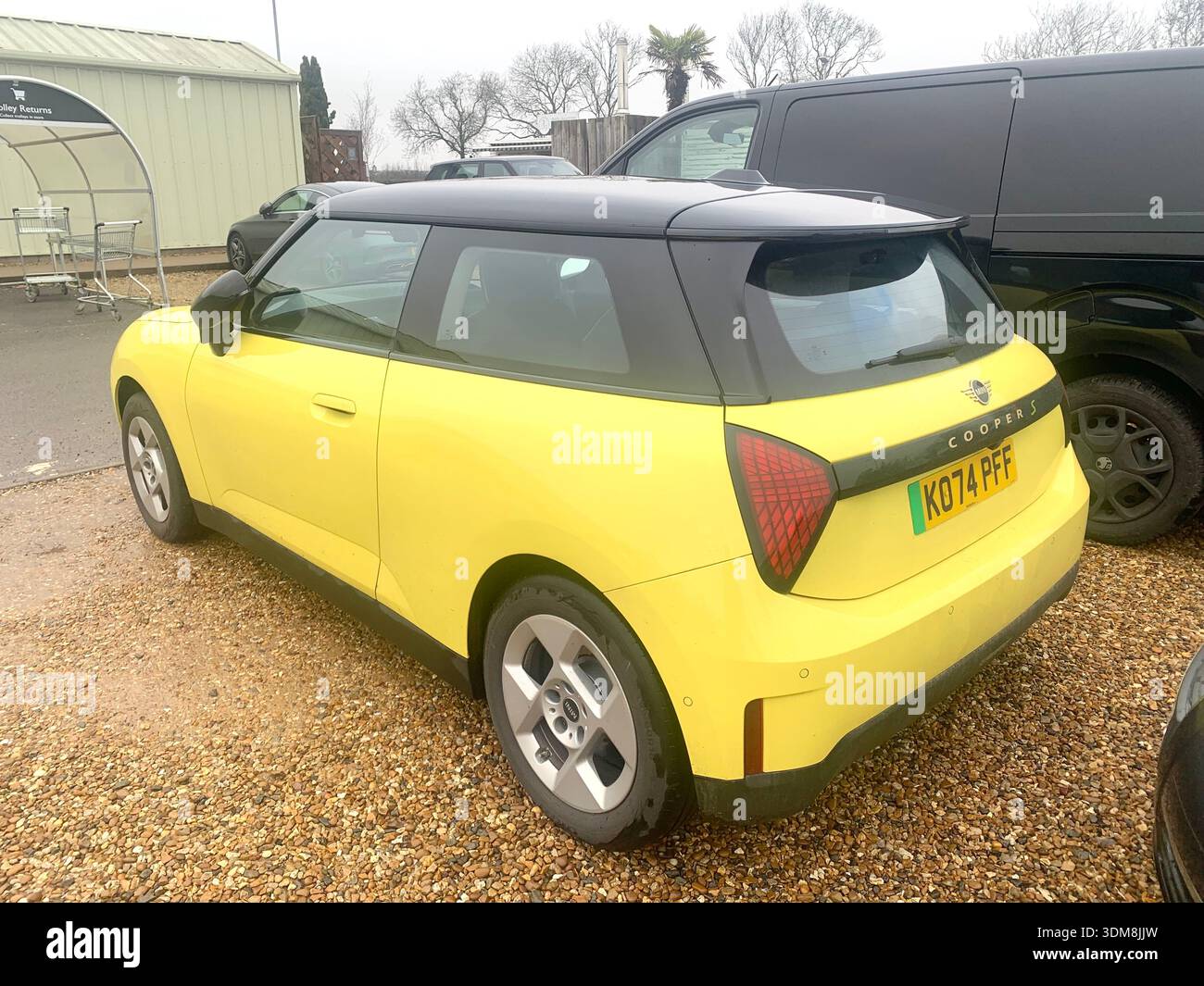 Yellow and Black ORA electric car parked in a UK supermarket car Park Mini cooper S parked near trolleys and other vehicles in the background - Smartphone Captured Stock Image