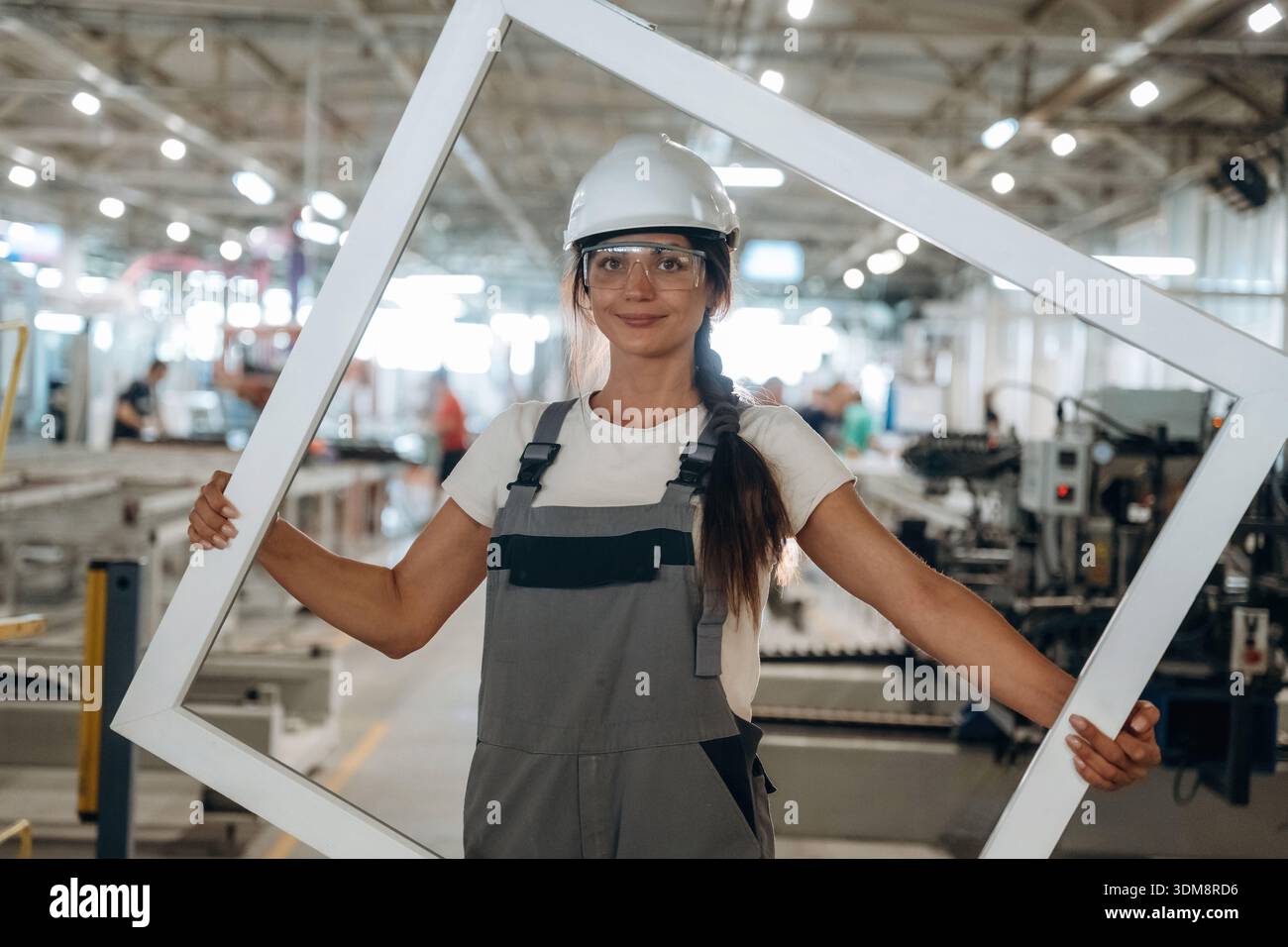 Big frame in hands. Woman is in the window making factory. Stock Photo